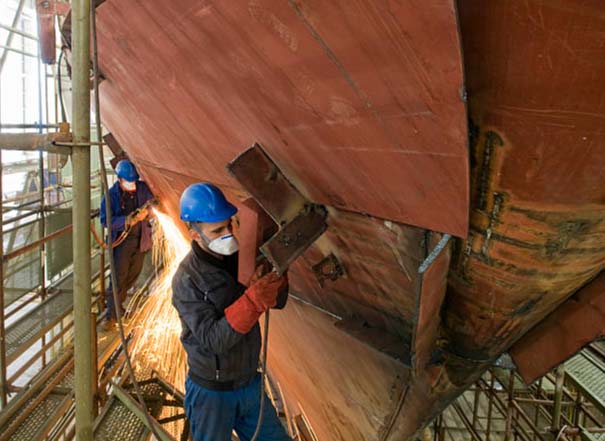 Workers replacing a hull plate with AH36DH36 steel during ship repair in a dry dock